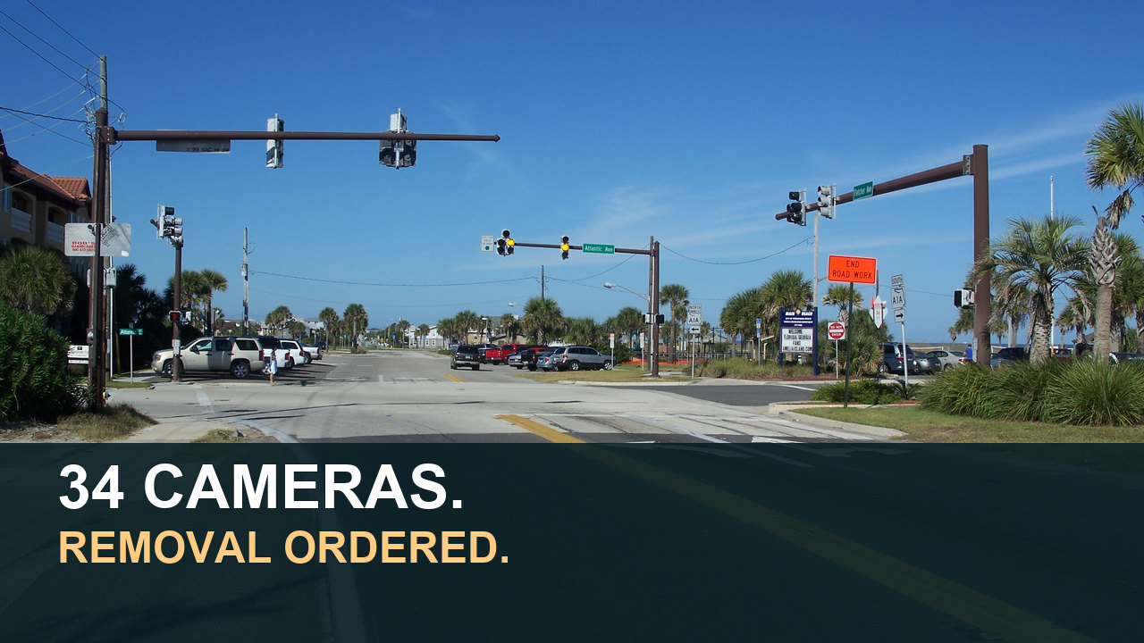 2010 photograph of the A1A and SR 200 intersection in Fernandina Beach with text reading 34 cameras, removal ordered. No Flock camera is identified in the photo.